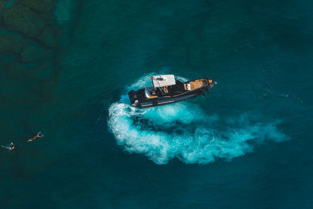 Barco a motor con bañistas en agua turquesa vista desde el aire