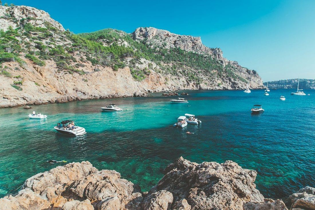 Bahía con barcos fondeados frente a los acantilados